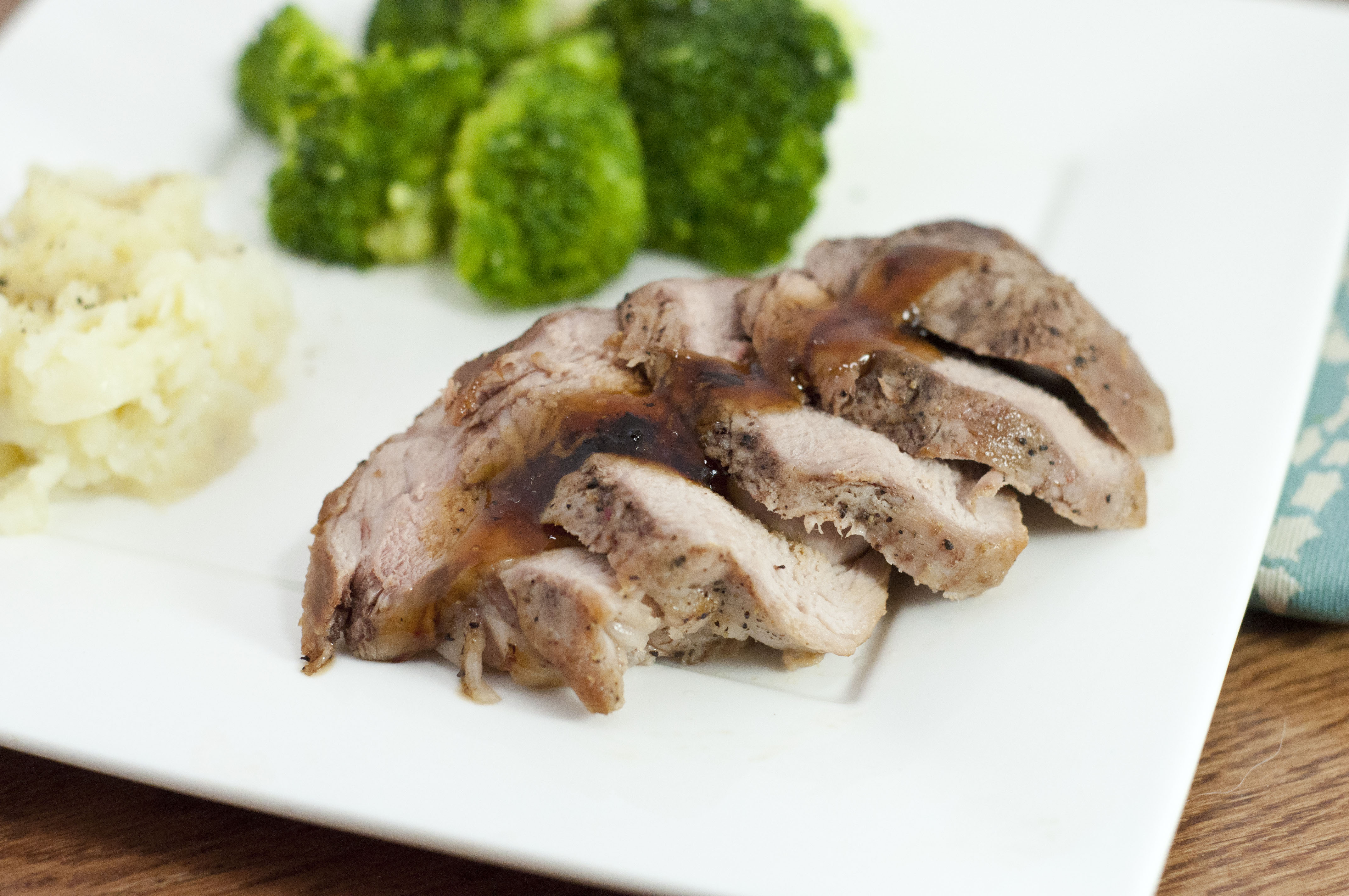 an image of brined teriyaki pork tenderloin with broccoli and potato in the background