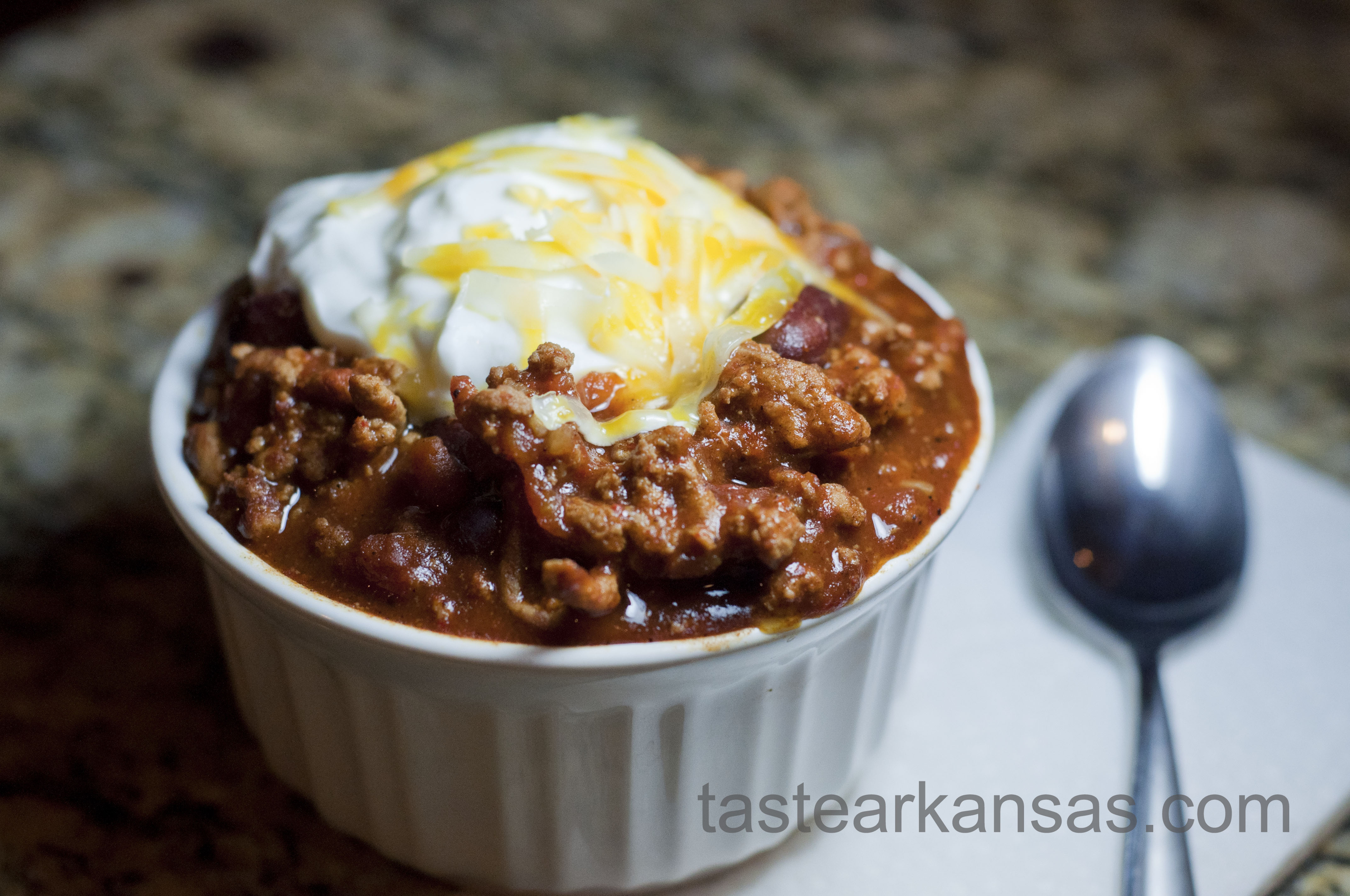 a steamy bowl of chili with a dollop of greek yogurt and shredded cheese